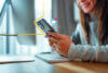 Frau hält ein Handy - im Bild ist ein gängiges Icon ergänzt, dass "eingehende E-Mail" bedeutet.