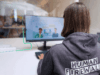 Frau mit Pullover "Human Firewall" sitzt vir dem PC und macht eine Schulung. IT-Security Beratung