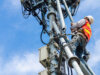 Kreth & Vogt - Referenzkunde von ORBIT: Symbolbild für das Thema Standortgenehmigung: Techniker in Schutzkleidung (Helm und Warnweste) arbeitet an einem hohen Antennenmast.